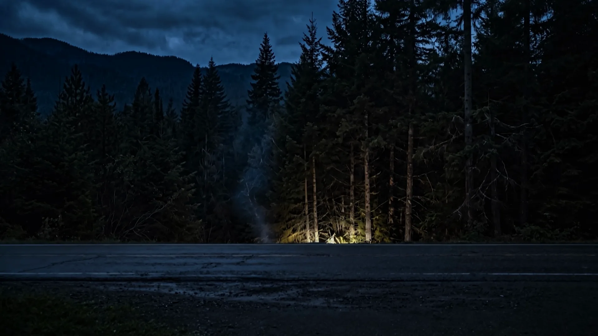 Wide shot of the wrecked car against a tree at the edge of the road, one headlight alive, steam rising.